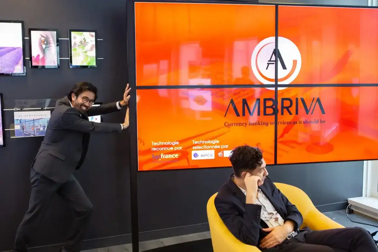Équipe Ambriva dans un bureau moderne avec écran présentant leurs solutions de change
